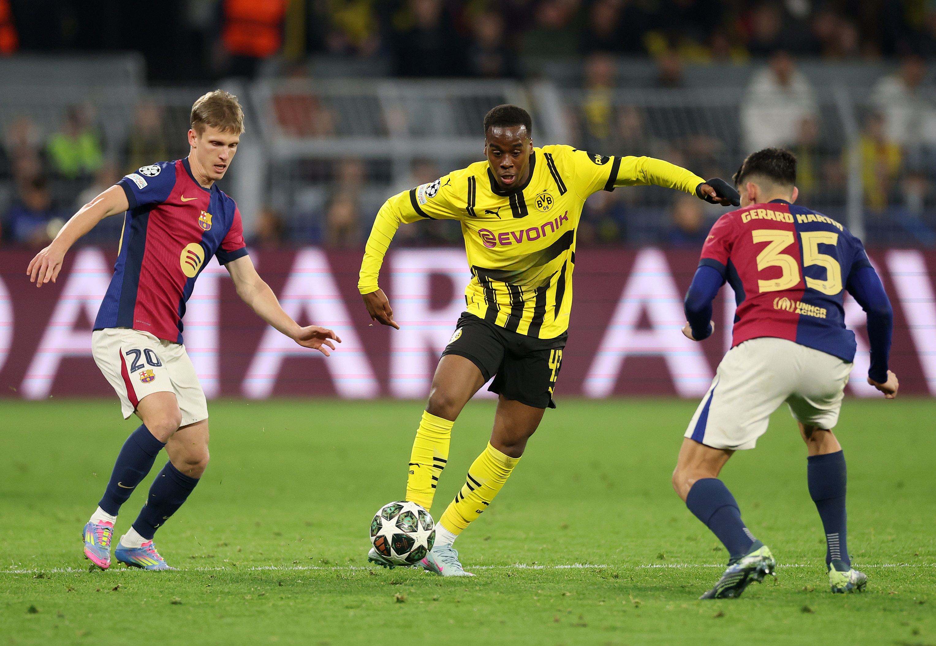 Jamie Gittens dribbles between two Barcelona players.