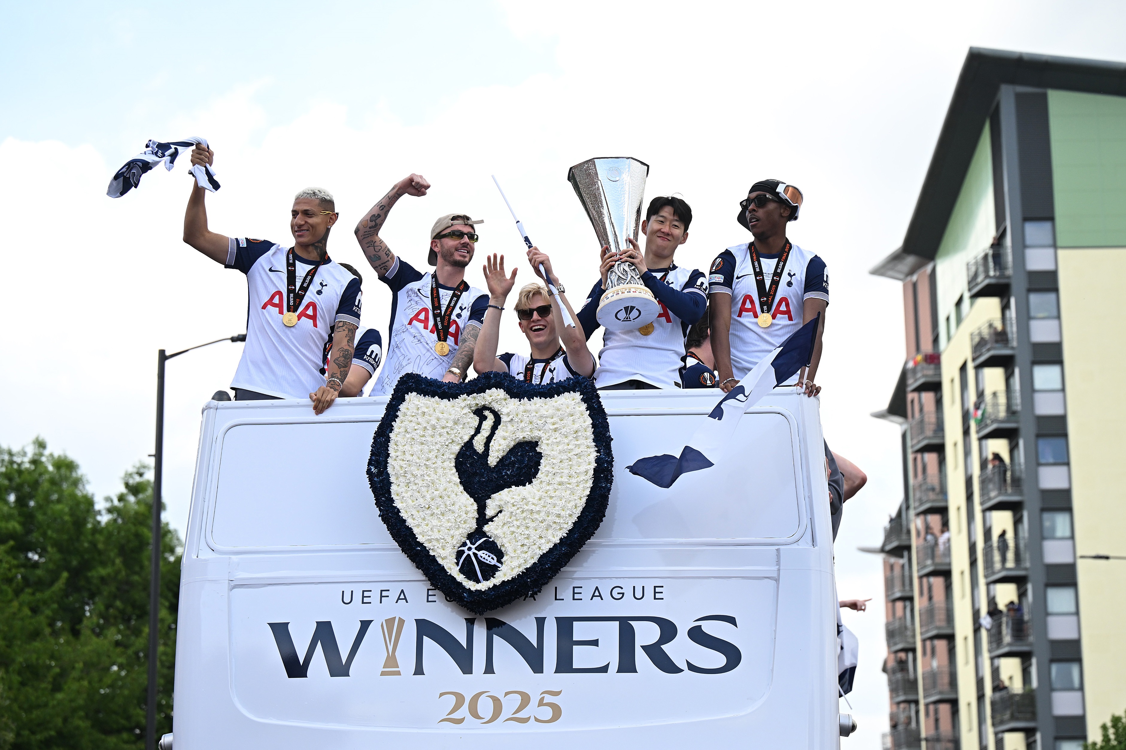 Mathys Tel stands on an open top bus with the Europa League trophy.