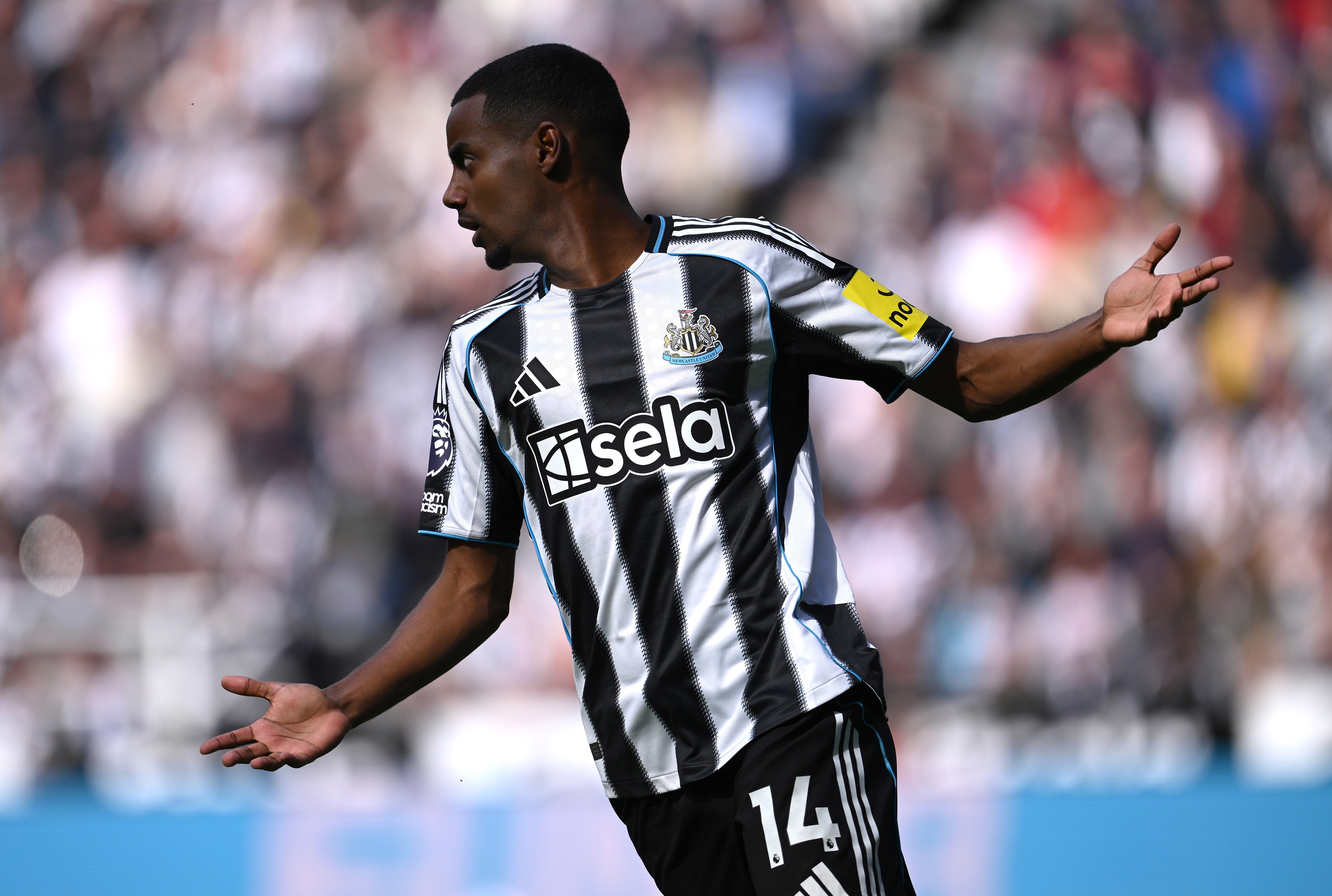 Alexander Isak holds up his arms whilst looking off in the distance.