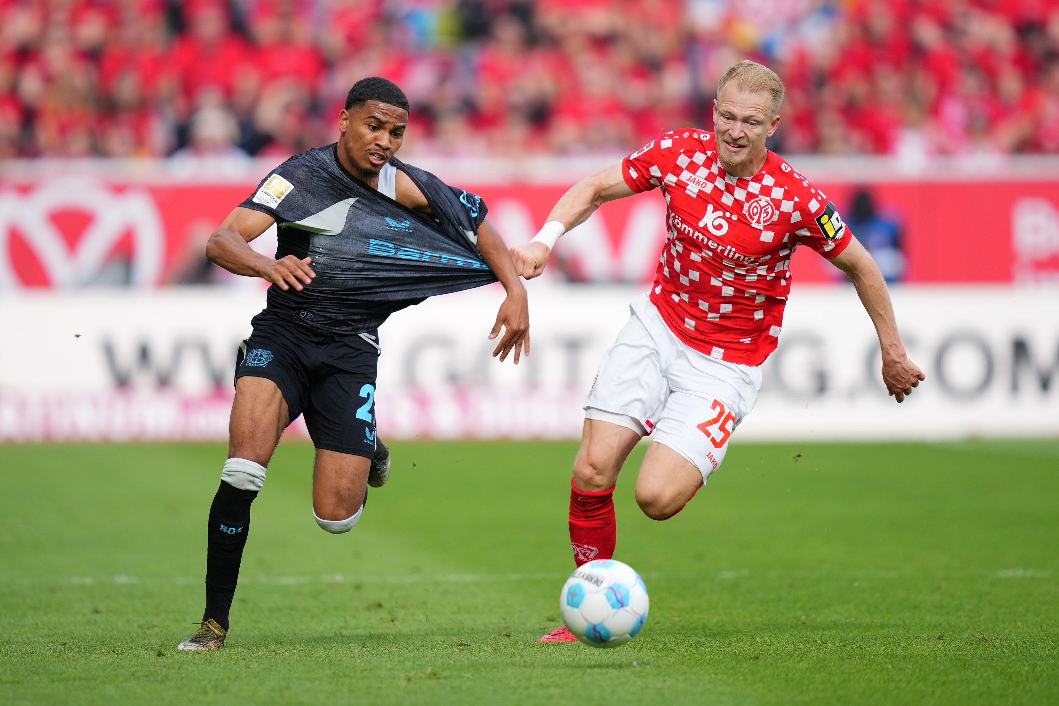 Amine Adli has his shirt pulled by a Mainz player.