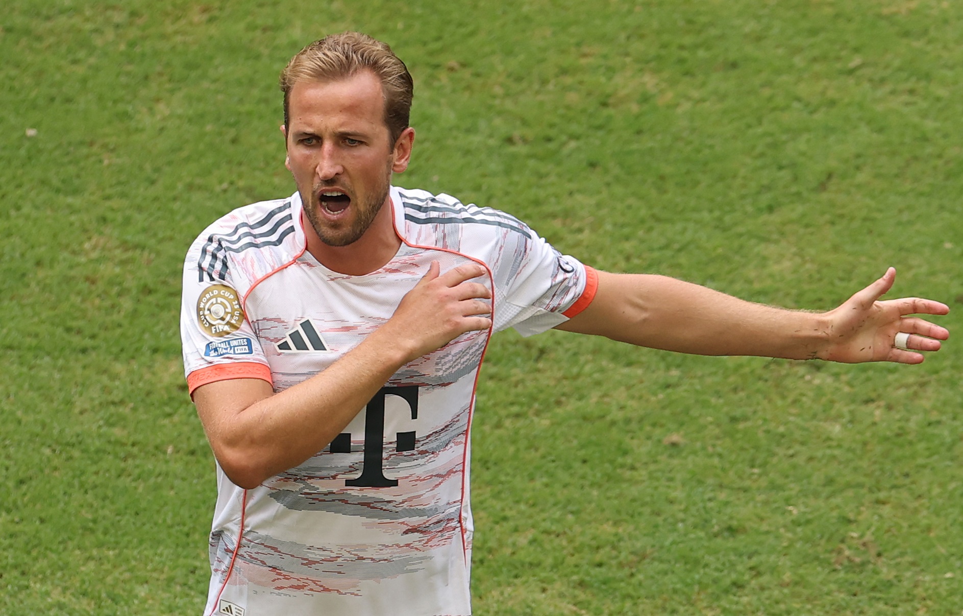 Harry Kane shouts and holds out his left arm.