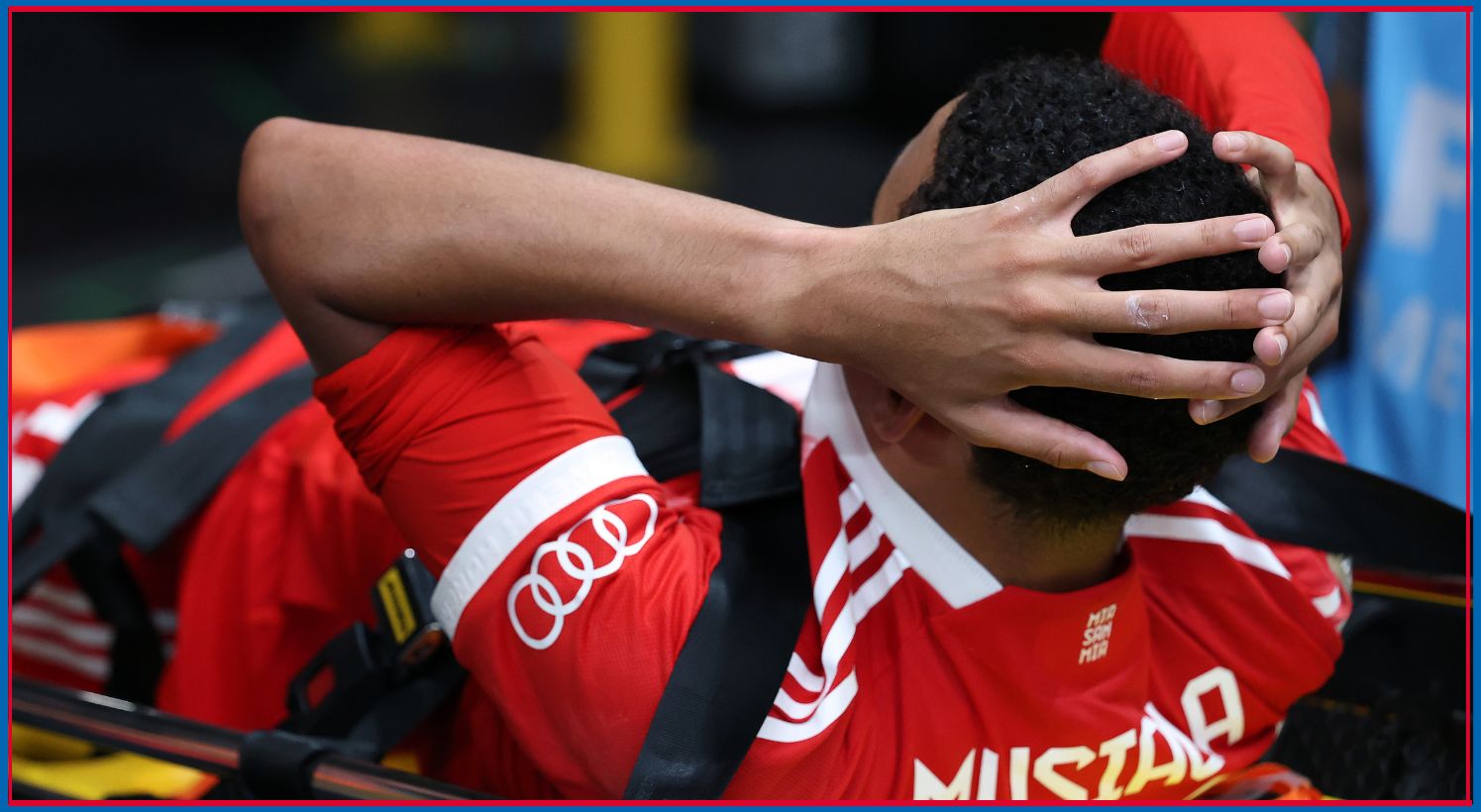 Jamal Musiala holds his head whilst lying on a stretcher.