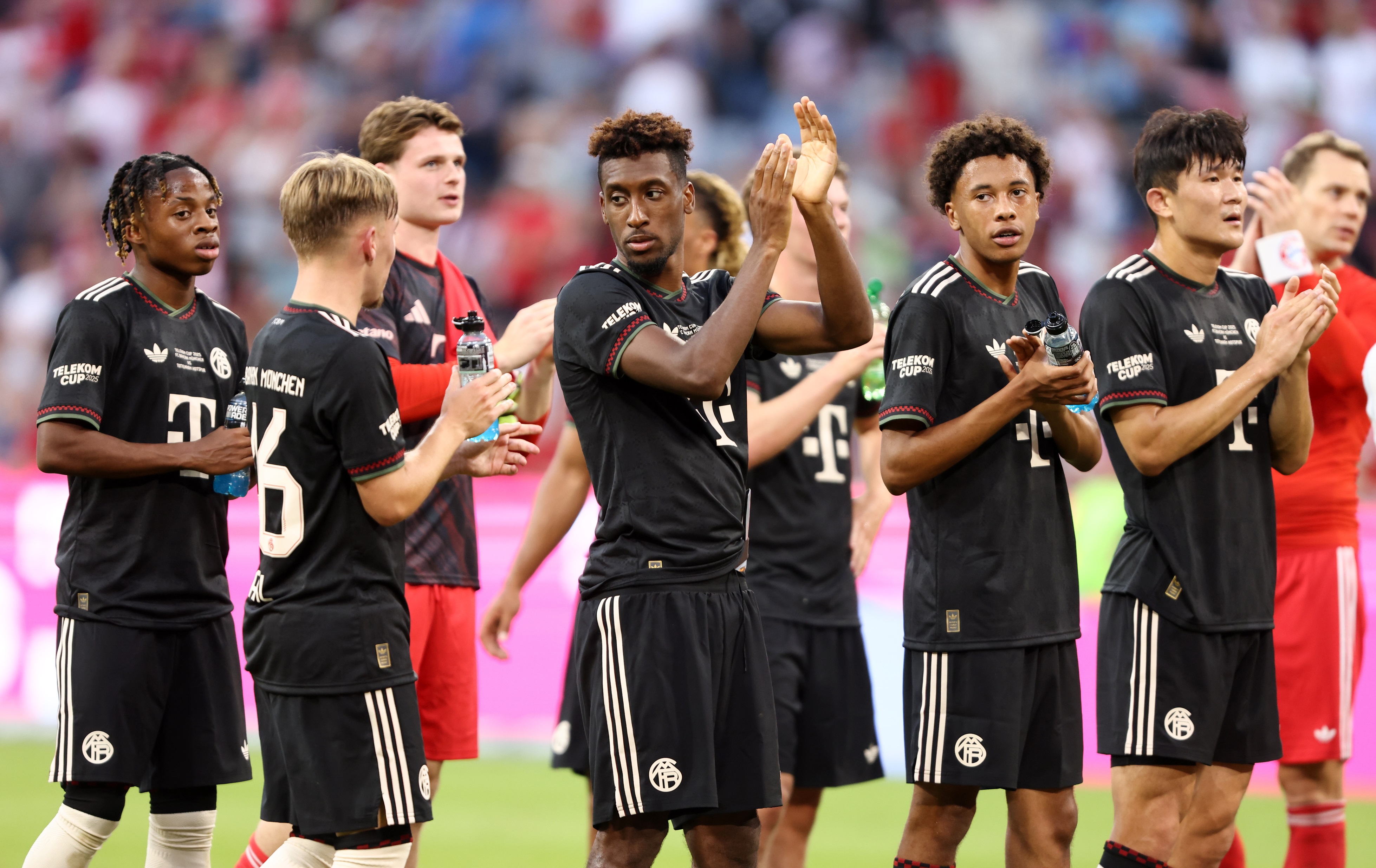 Kingsley Coman claps his hands whilst standing alongside Bayern Munich teammates.
