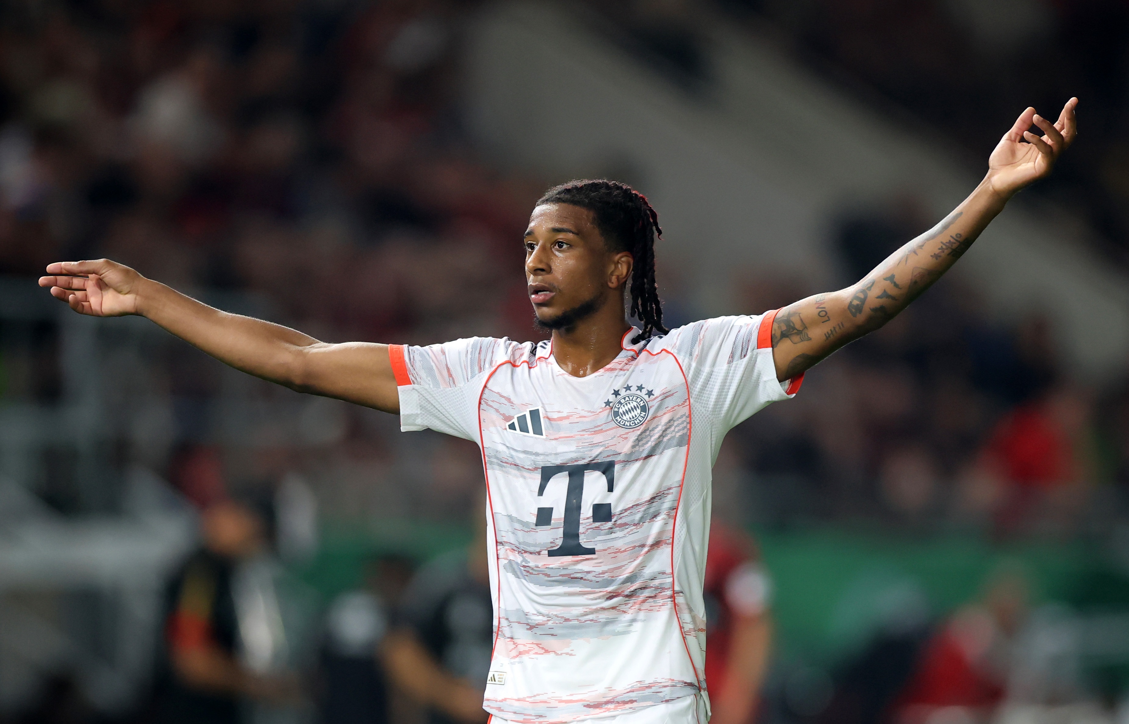 Michael Olise holds his arms out wide during Bayern Munich game.