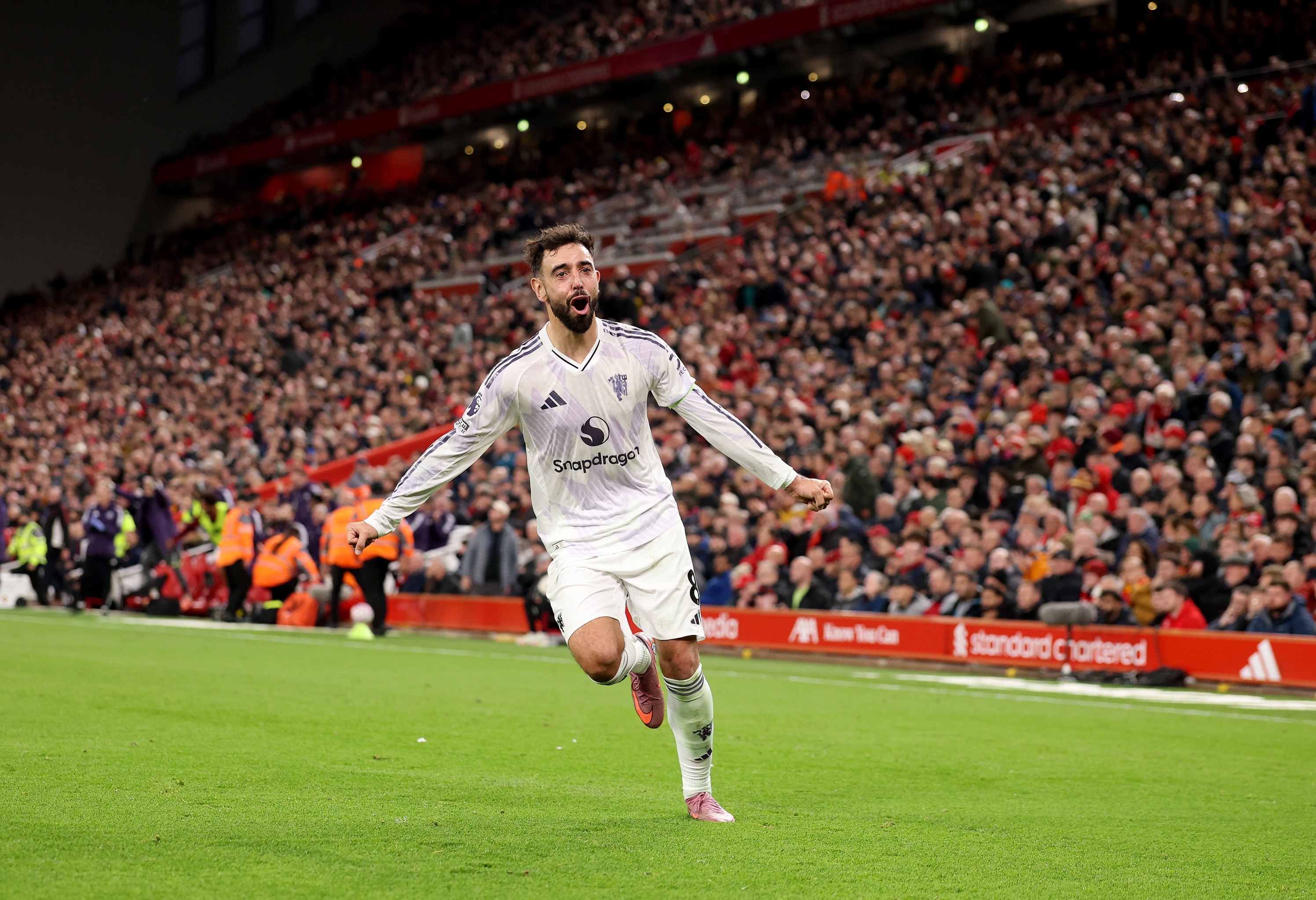 Bruno Fernandes runs and holds his arms out in celebration.