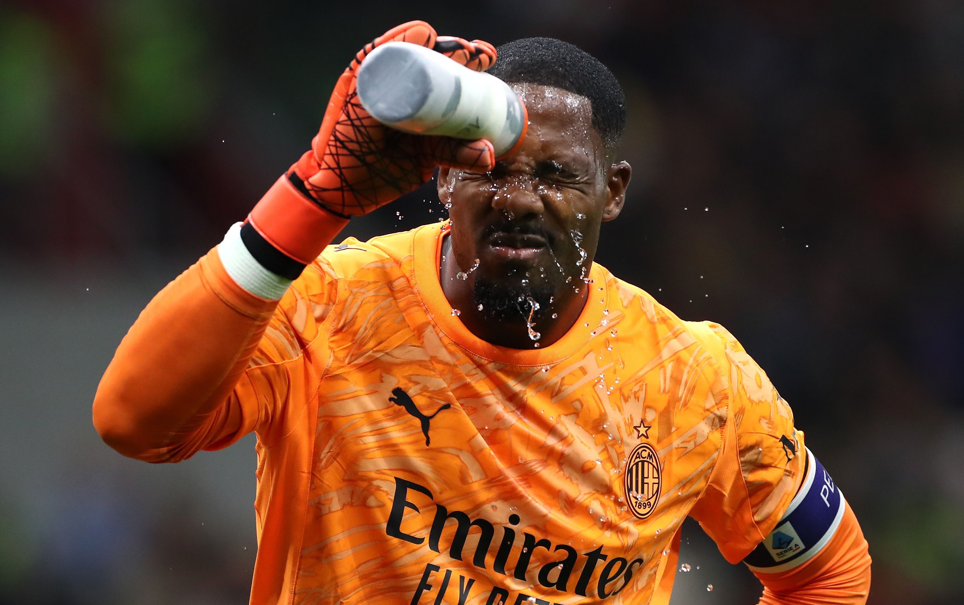 Mike Maignan sprays water on his face from his water bottle.