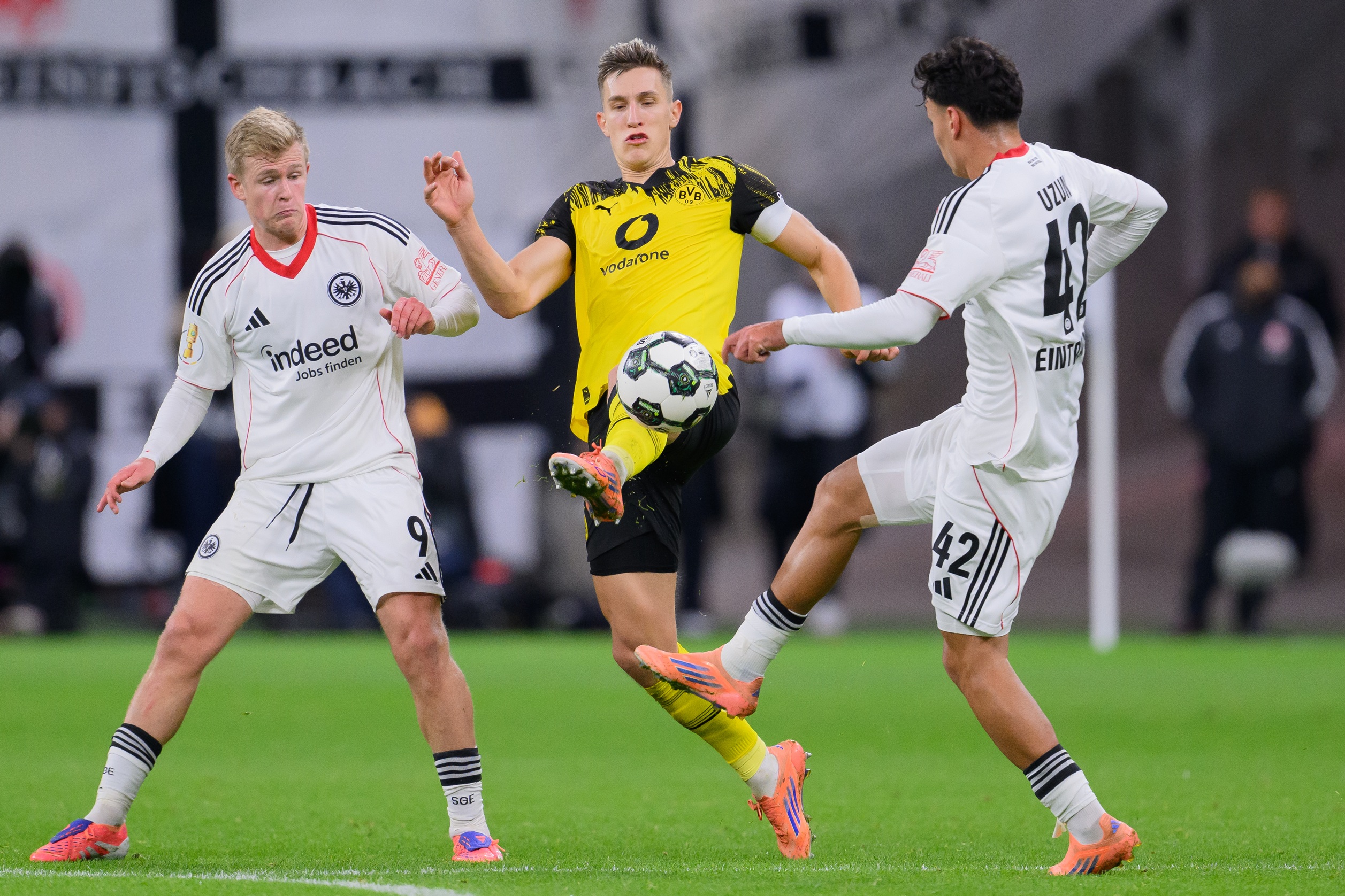 Nico Schlotterbeck kicks a ball while being surrounded by two Frankfurt players.
