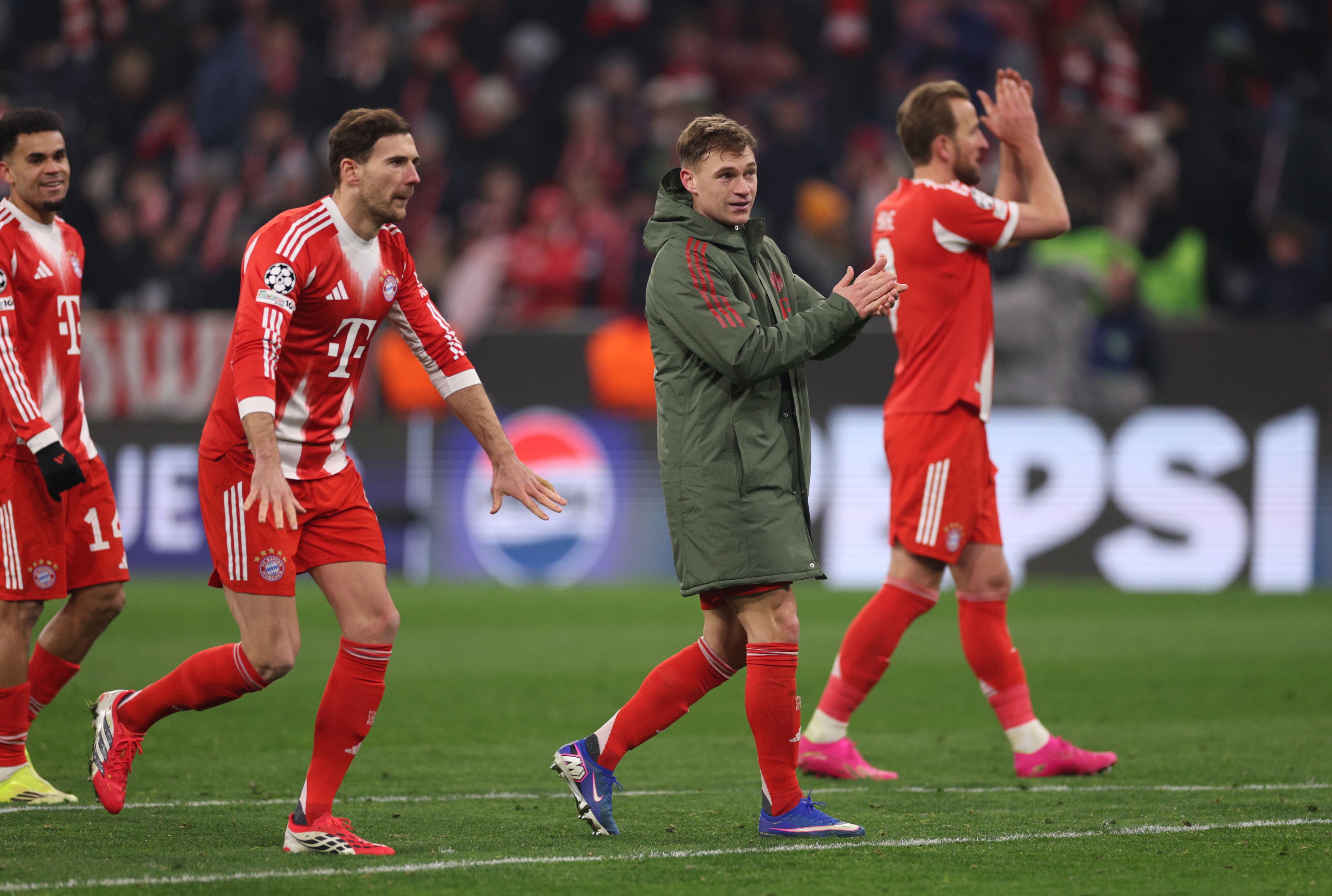 Leon Goretzka holds his arms down low as his Bayern teammates applaud.