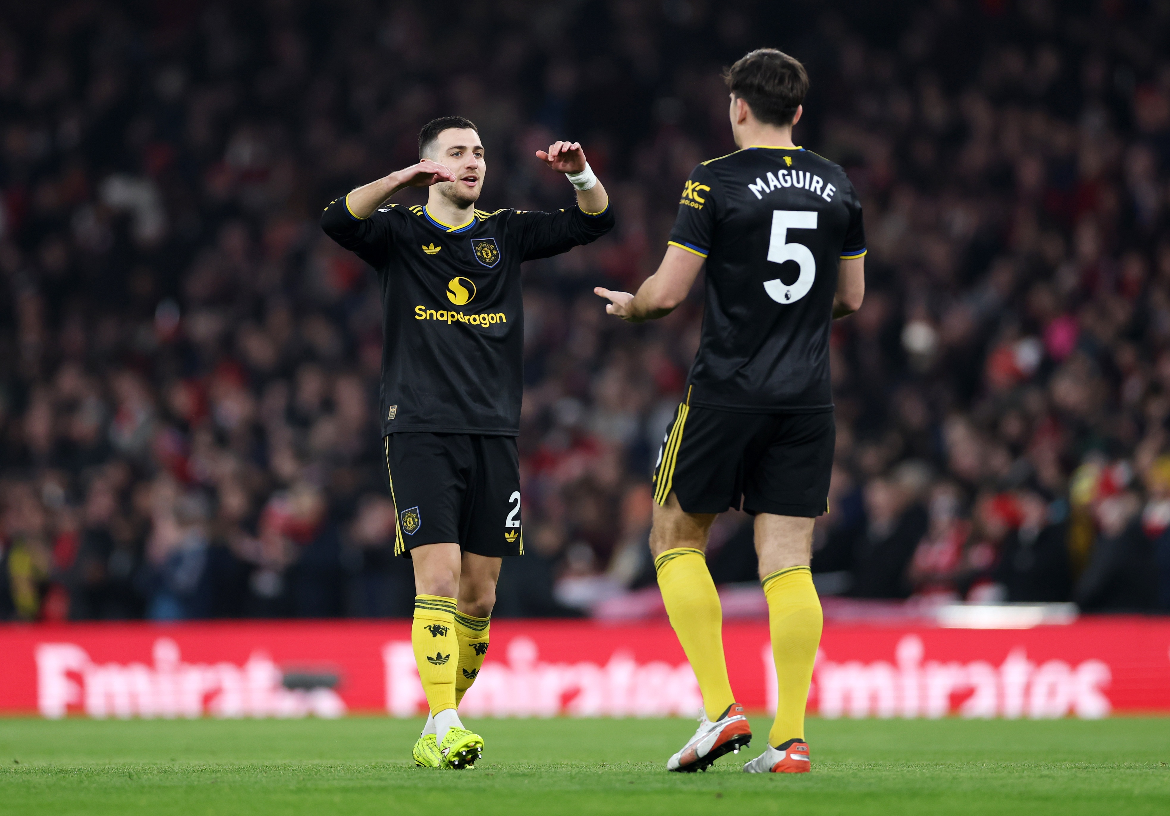 Diogo Dalot high-fives Harry Maguire.