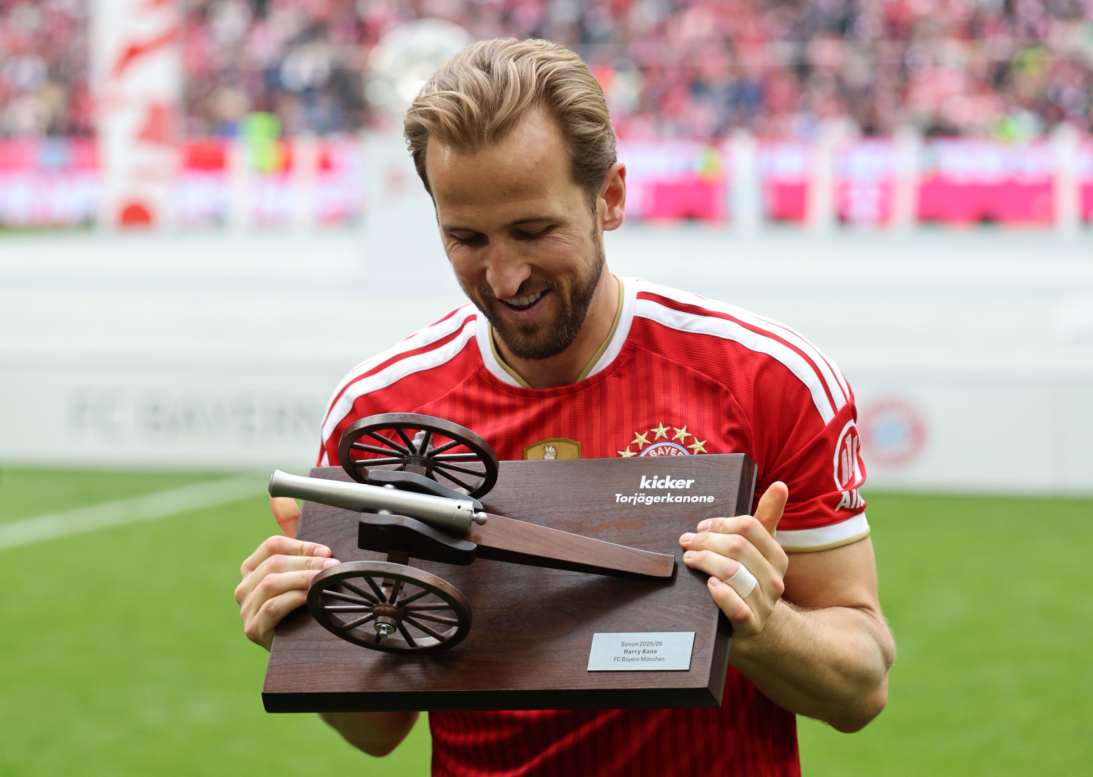 Harry Kane smiles as he looks down at the Top Scorer Cannon trophy.