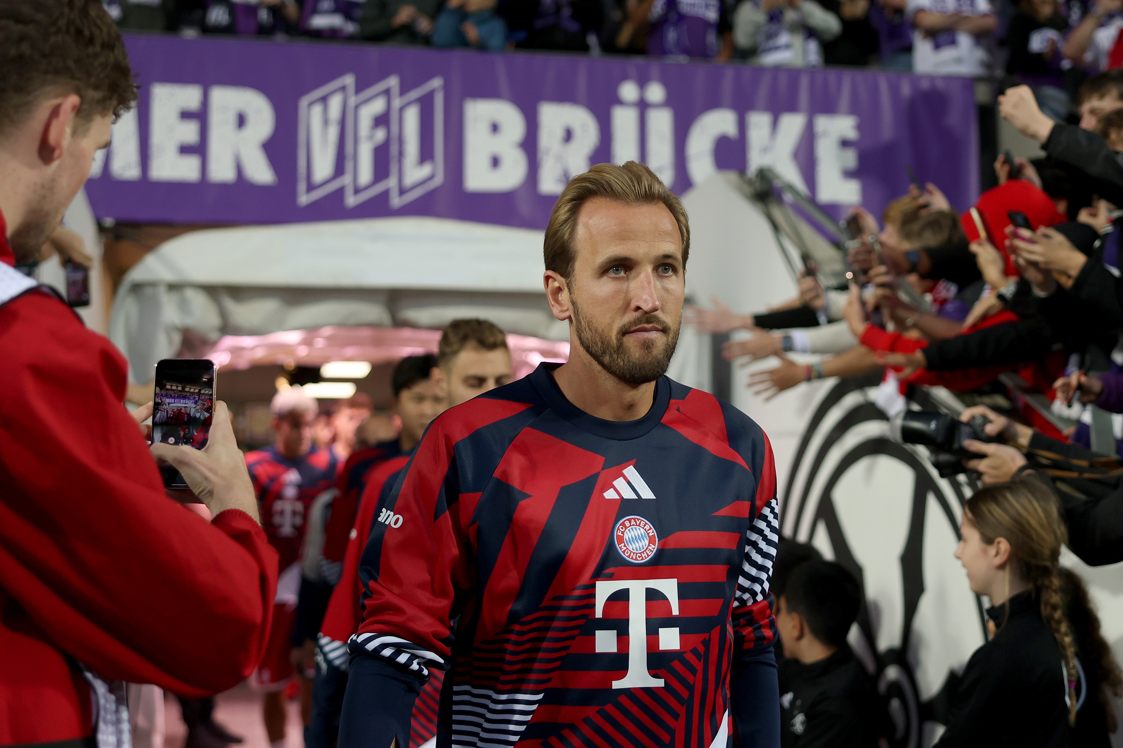Harry Kane walks out on to the pitch in front of a queue of Bayern Munich players.