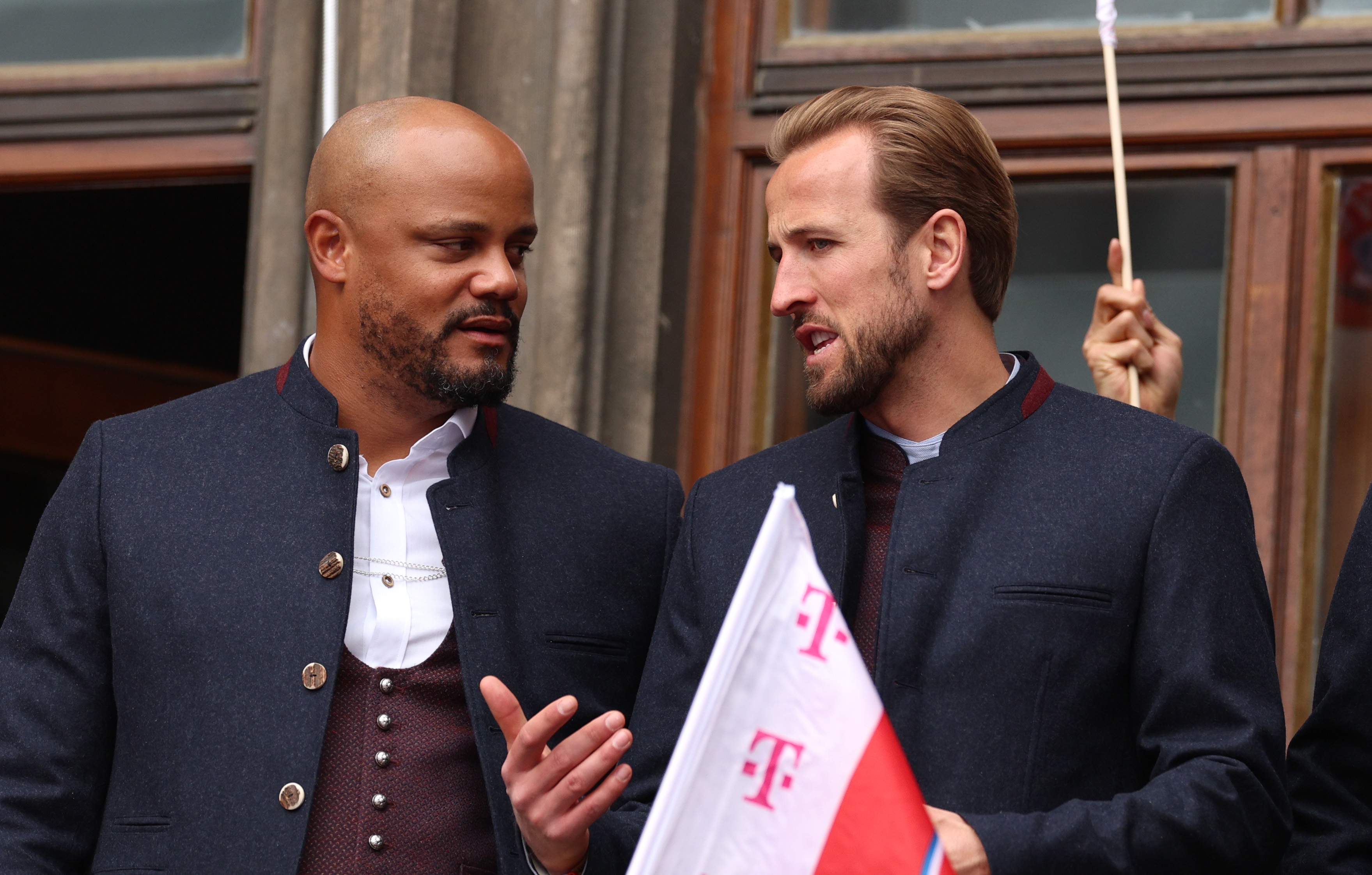 Harry Kane speaks with Bayern Munich head coach Vincent Kompany on a balcony.
