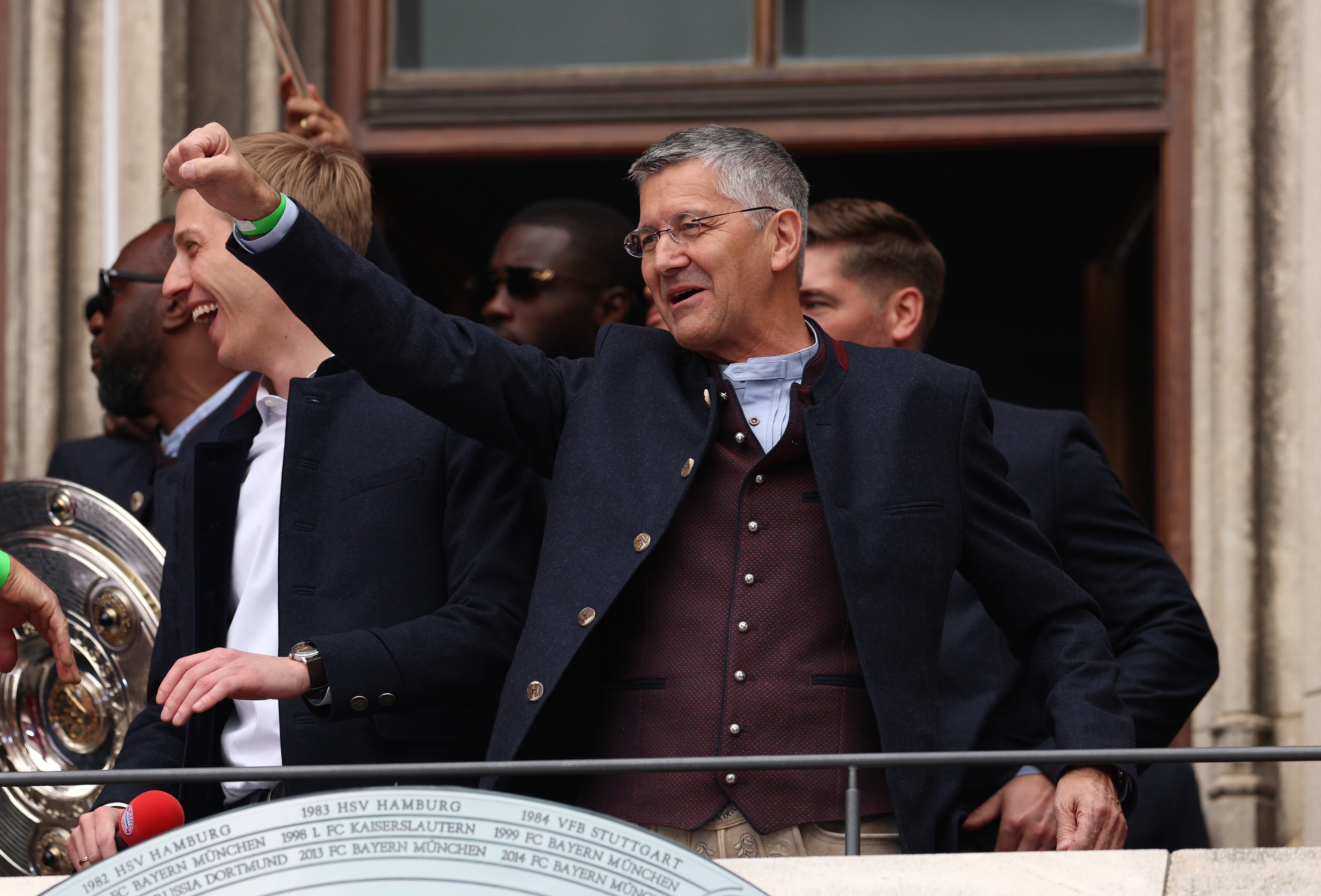Bayern president Herbert Hainer raises his fist to a crowd from a terrace.