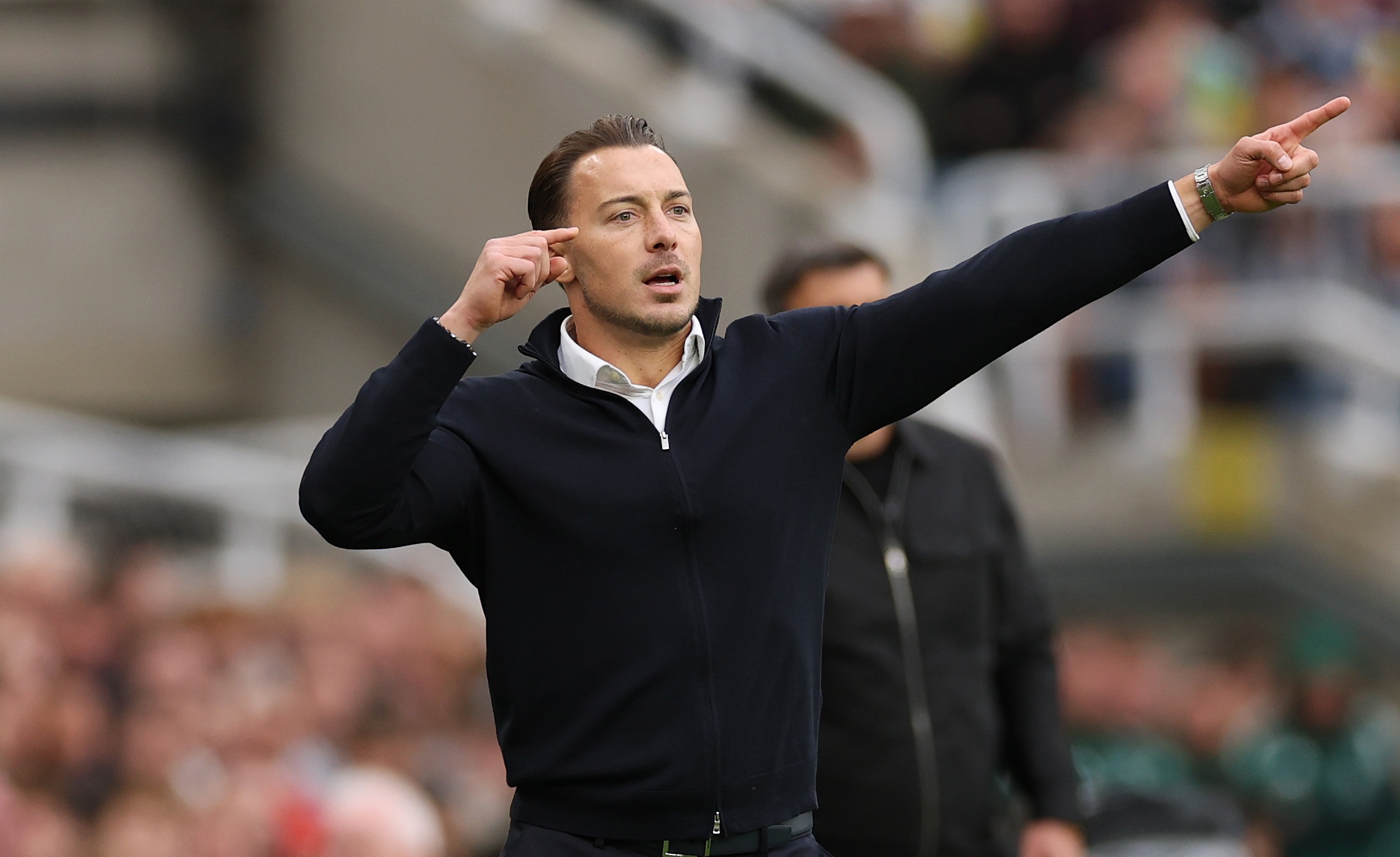 Newcastle head coach Matthias Jaissle points at his head.