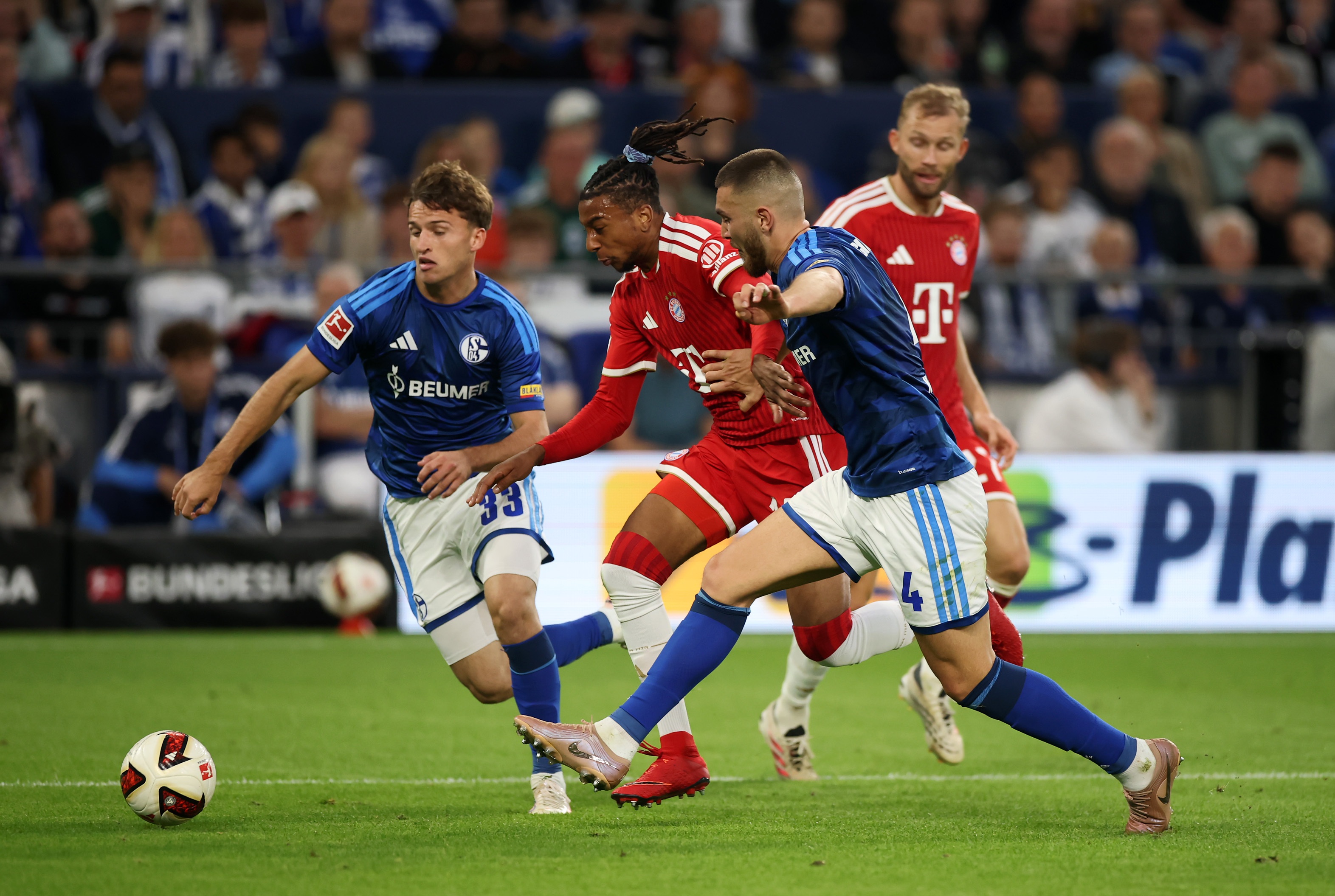 Bayern Munich winger Michael Olise dribbles in between two Schalke players.